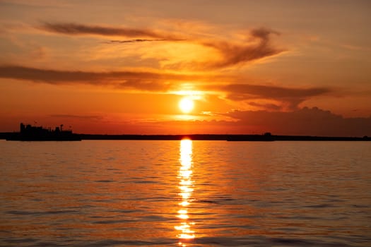 Sunset on the embankment of the Amur river in Khabarovsk. The sun set over the horizon. The embankment is lit by lanterns.