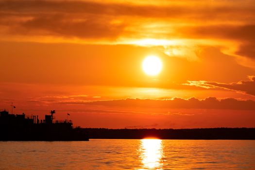 Sunset on the embankment of the Amur river in Khabarovsk. The sun set over the horizon. The embankment is lit by lanterns.