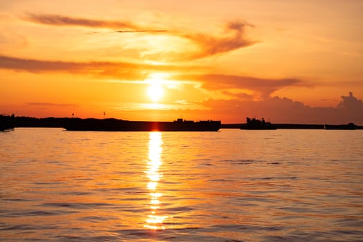 Sunset on the embankment of the Amur river in Khabarovsk. The sun set over the horizon. The embankment is lit by lanterns.