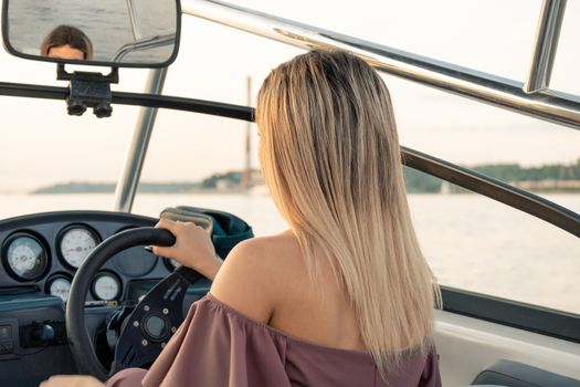 Young, beautiful and slender girl driving a speedboat on the Amur river