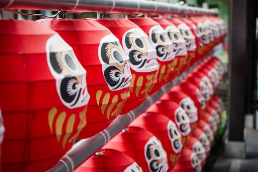 Daruma dolls. The Japanese lucky symbolic dolls hanging in the row with text translation “fortune”.