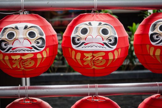 Daruma dolls. The Japanese lucky symbolic dolls hanging in the row with text translation “fortune”.