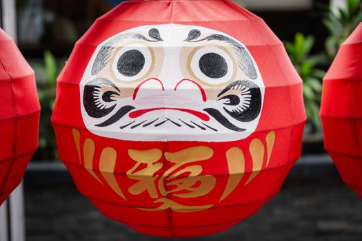 Daruma dolls. The Japanese lucky symbolic dolls hanging in the row with text translation “fortune”.