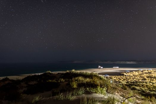 Bright lights of Coral Bay during night in front of dark night sky in Australia