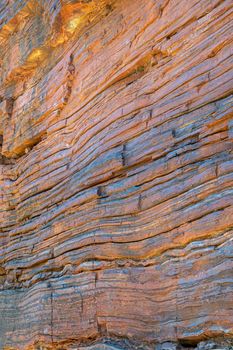 Layers of natural asbestos shining blue and iron ore rich sediment shining red at Karijini National Park Australia