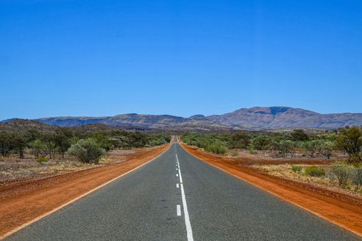 Perfect straight road between red dust at Karijini National Park Australia