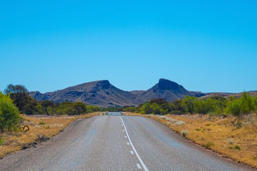 Straight road leading towards gap in between two mountain tops at Karijini National Park Australia