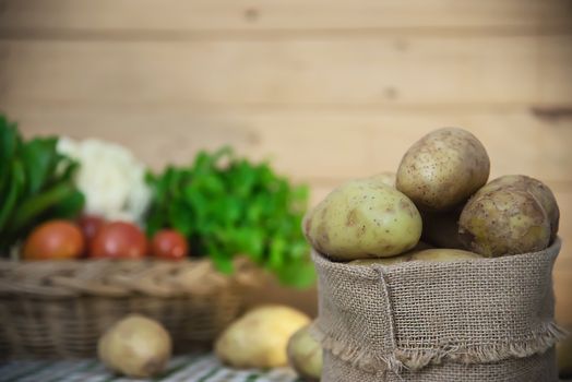 Fresh potato ready for cooking with potato sack background - potato cooking concept