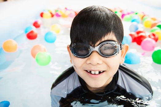 Boy playing with colourful ball in small swimming pool toy - happy boy in water pool toy concept