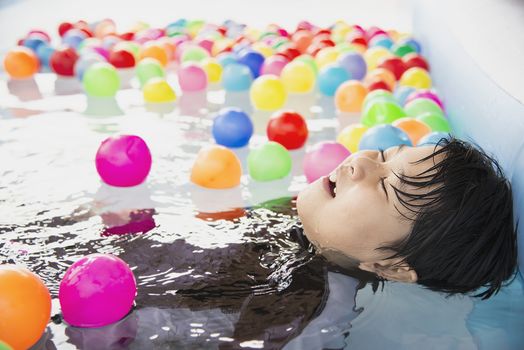 Boy playing with colourful ball in small swimming pool toy - happy boy in water pool toy concept