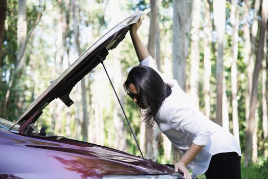 Asian woman calling repairman or insurance staff to fix a car engine problem on a local road - people with car problem transportation concept