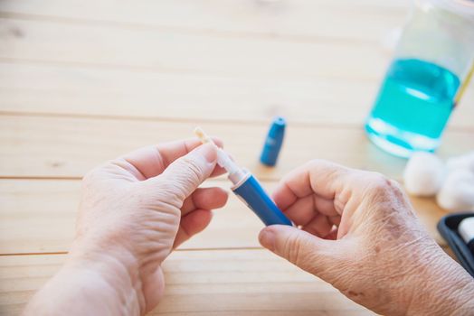 Old lady is testing blood sugar level using blood sugar test kid set - people with medical equipment concept