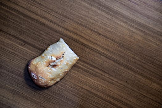 A piece of home made, white flour bread over a wooden table in Mutilva, Spain. 
Zenith view