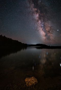 Milky Way and pink light at mountains. Night colorful landscape. Starry sky with hills at summer. Beautiful Universe. Space background with galaxy. Travel background