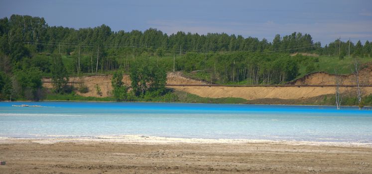 The lake with beautiful water is a pale blue color surrounded by a pine forest. Novosibirsk, Siberia, Russia.