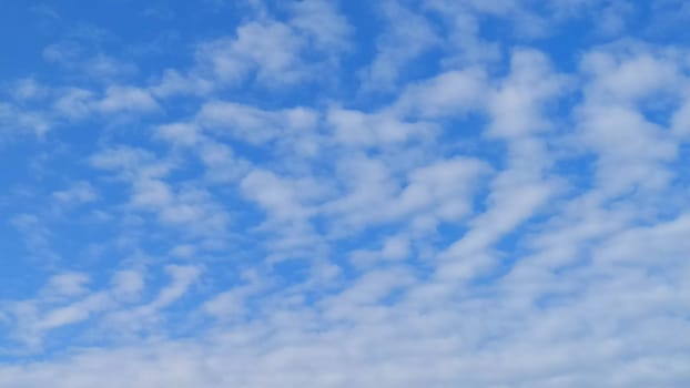 A fragment of a blue sky covered with white cumulus clouds.