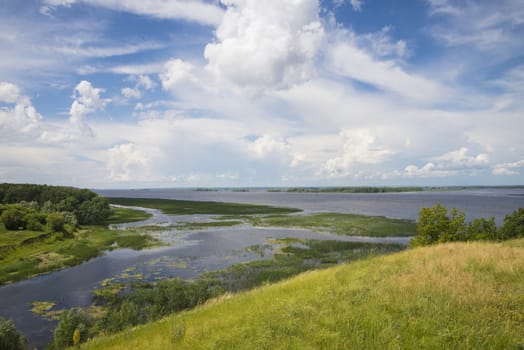 Panoramic view of the river, meadows and clouds. Summer landscape of nature