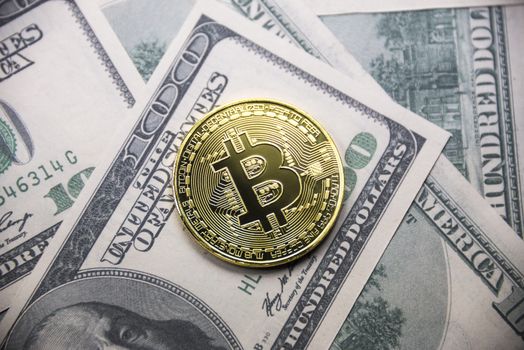 Gold coin Bitcoin on the background of hundred dollar bills.