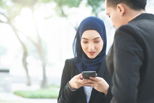 Muslim business women using mobile phone outdoor.