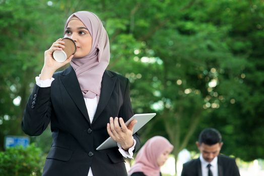 Muslim business woman drinking coffee while going to work in morning.