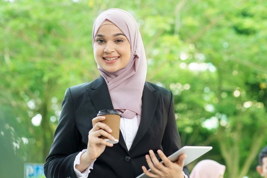 Muslim business woman drinking coffee while going to work in morning.