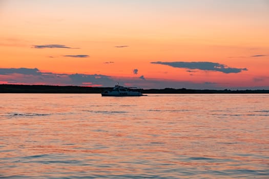 Sunset on the embankment of the Amur river in Khabarovsk. The sun set over the horizon. The embankment is lit by lanterns.