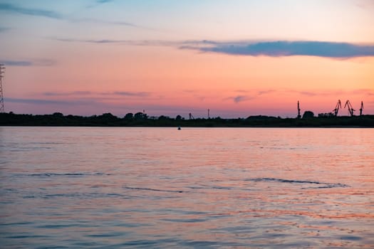 Sunset on the embankment of the Amur river in Khabarovsk. The sun set over the horizon. The embankment is lit by lanterns.