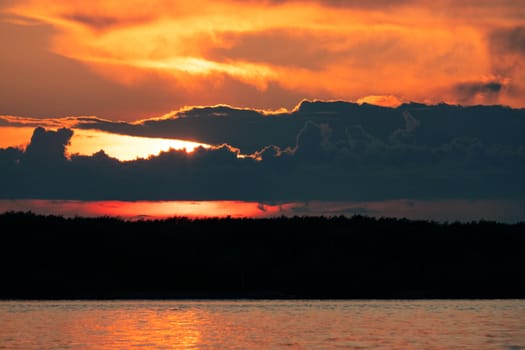 Sunset on the embankment of the Amur river in Khabarovsk. The sun set over the horizon. The embankment is lit by lanterns.