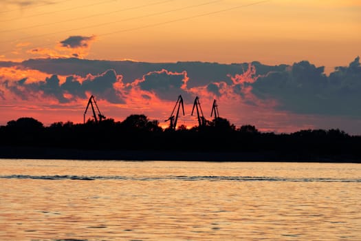 Sunset on the embankment of the Amur river in Khabarovsk. The sun set over the horizon. The embankment is lit by lanterns.