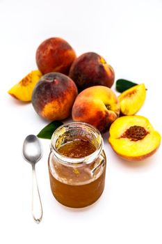 Composition of a bunch of peaches with a jar of jam on a white background
