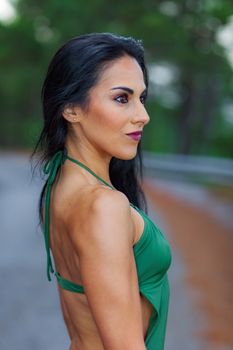 Fitness girl posing in the beach forest with a beautiful green swimsuit