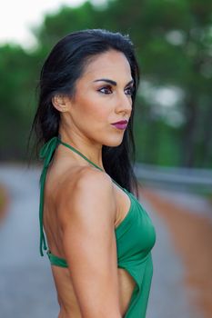 Fitness girl posing in the beach forest with a beautiful green swimsuit