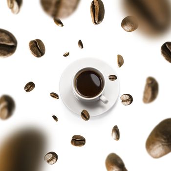 Cup of coffee and coffee beans in flight on white background.