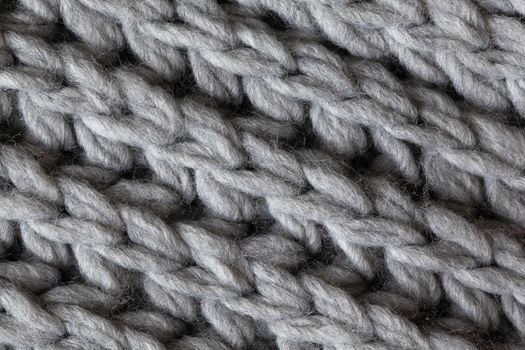 Knitted woolen textured surface, macro. Soft grey merino wool pattern backdrop, closeup. Autumn and winter flat lay. Scandinavian minimal style.