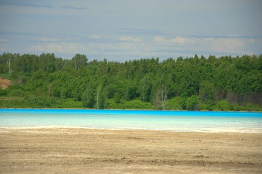 Blue forest lake with tall pine trees on the shore. Novosibirsk, Russia.