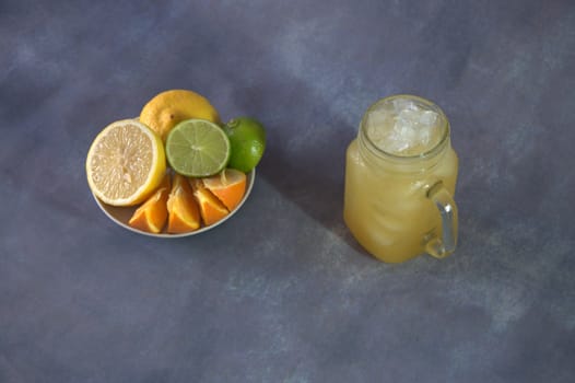 Slices of orange, lime and lemon on a saucer and a glass mug with ice and citrus juice.