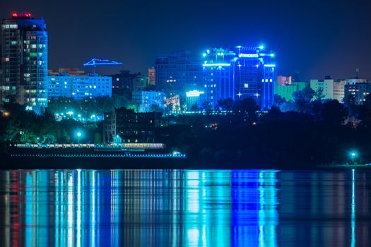 Night View of the city of Khabarovsk from the Amur river. Blue night sky. The night city is brightly lit with lanterns