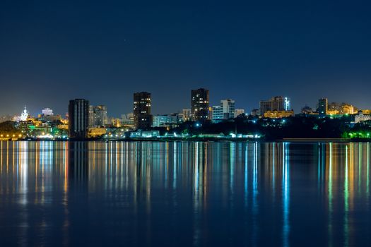 Night View of the city of Khabarovsk from the Amur river. Blue night sky. The night city is brightly lit with lanterns