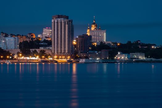 Night View of the city of Khabarovsk from the Amur river. Blue night sky. The night city is brightly lit with lanterns