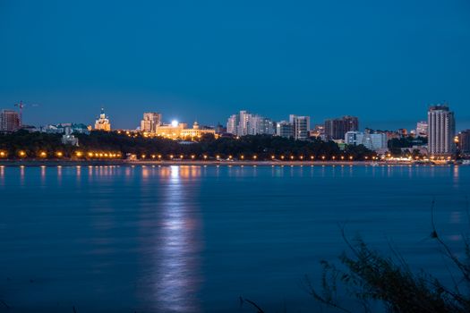 Night View of the city of Khabarovsk from the Amur river. Blue night sky. The night city is brightly lit with lanterns