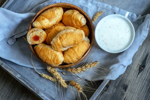 Croissants, a cup with kefir and ears of grain on a wooden tray. The concept of a wholesome breakfast