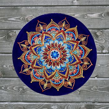 Decorative ceramic plate, hand painted with acrylic paints on a wooden background. A square photo closeup