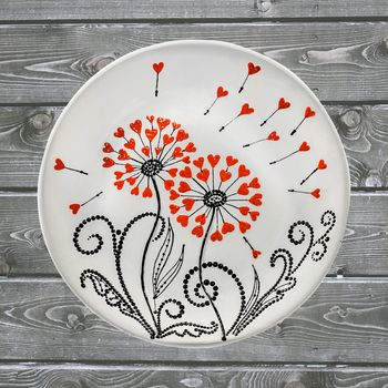 Decorative ceramic plate, hand painted with acrylic paints on a wooden background. A square photo closeup