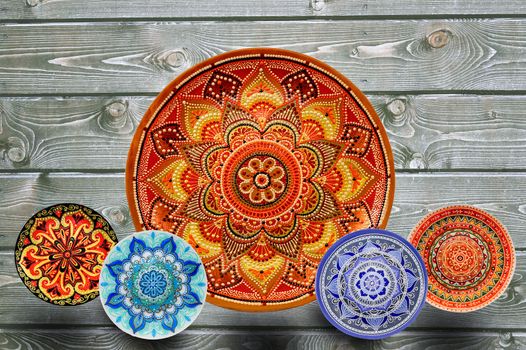 Set of decorative ceramic plates hand-painted with acrylic paints on a wooden background with place for text