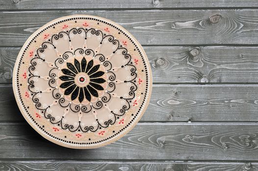 Decorative ceramic plate, hand painted with acrylic paints on a wooden background. Closeup with place for text