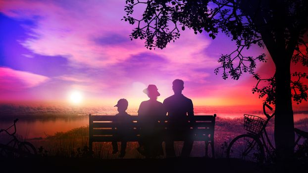 Silhouettes of family with a child sitting on a park bench and watching sunset over the river.
