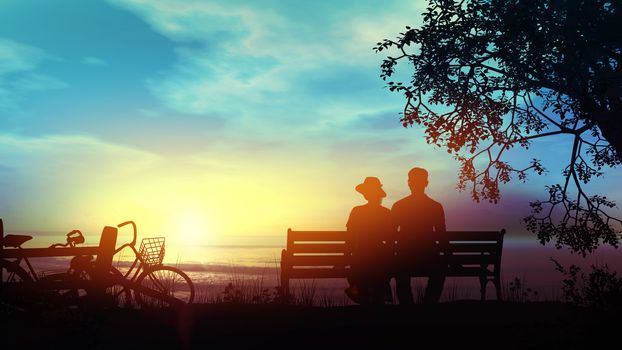 Silhouettes of a couple sitting on a bench and looking at the setting sun over the ocean.