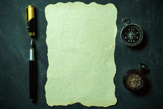 Vintage paper and pen with compass and pocket watch on black background. Top view and copy space for text.