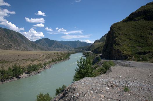 A turquoise river flows at the foot of sheer cliffs. Katun, Altai, Siberia, Russia.