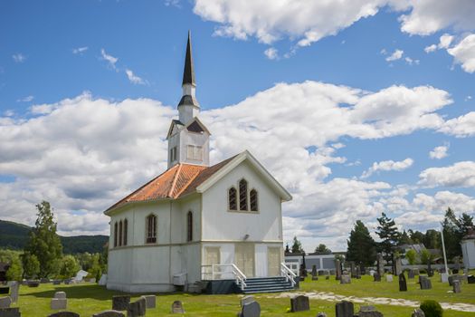white wooden stave church near Leira in Norway with cemetery
